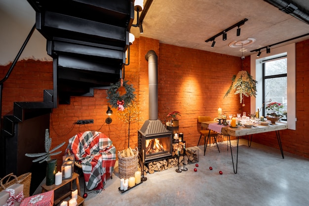 Hermoso interior de estilo loft con chimenea y mesa de comedor decorada para las vacaciones de Año Nuevo