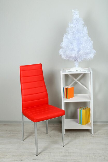 Foto hermoso interior con silla de color moderno, libros sobre soporte de madera, sobre fondo de pared