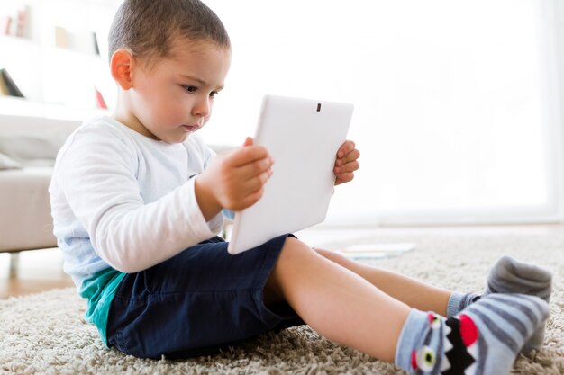 Hermoso joven utilizando su tableta digital en casa.