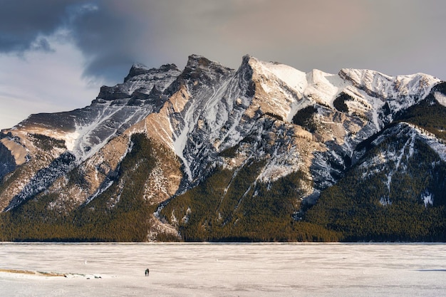 Hermoso lago congelado Minnewanka con montañas rocosas en invierno por la noche en el parque nacional de Banff