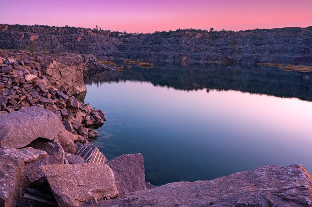 Un hermoso lago muy pequeño rodeado por grandes montones de desechos de piedra del trabajo duro en la mina