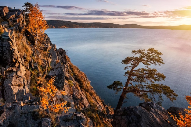 Hermoso lago y orilla rocosa en los rayos del sol vespertino del otoño dorado