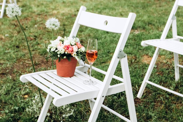 Un hermoso lugar para una ceremonia de boda en un claro en el bosque. Muchas sillas de madera blancas de pie en una fila. Ceremonia de boda de lujo al aire libre.