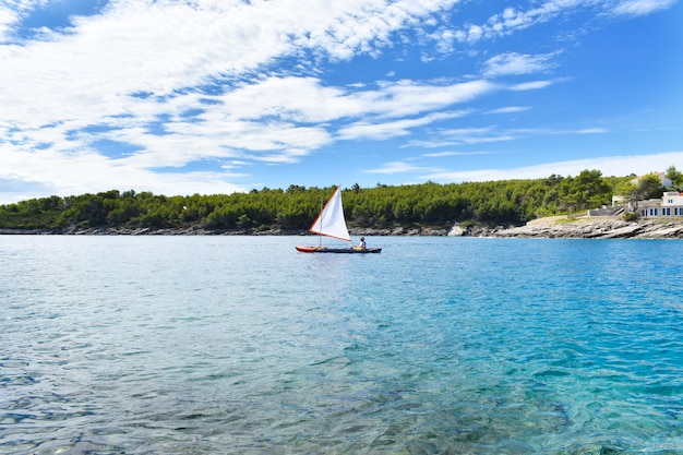 Hermoso mar Adriático. Pino verde, agua azul turquesa, tiempo soleado. Velero y marinero. Hvar Croacia, Europa.