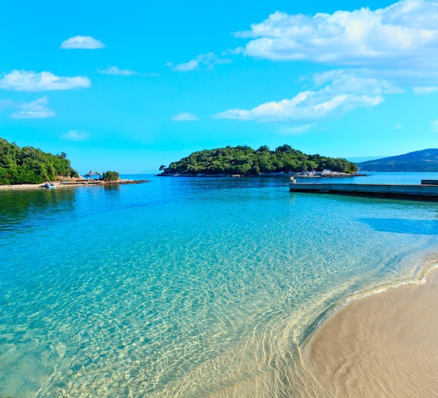 Hermoso mar Jónico con agua turquesa clara y vista de la costa de verano por la mañana desde la playa (Ksamil, Albania). Gente irreconocible.