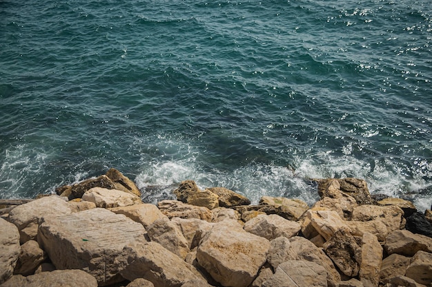 Hermoso mar Tirreno azul tranquilo Las olas rompen en las piedras blancas del rompeolas