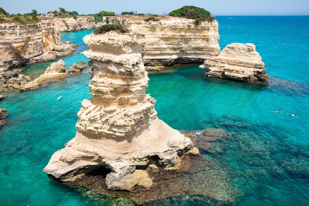 Hermoso mar turquesa con pilas y costa rocosa