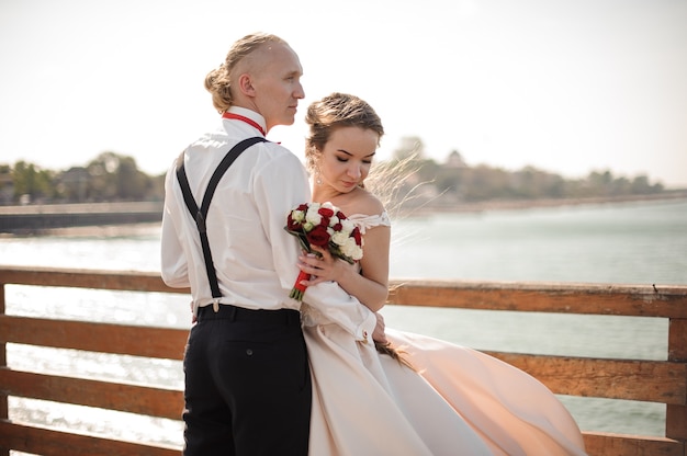 Hermoso matrimonio de pie en el muelle de madera del lago. Concepción de la boda