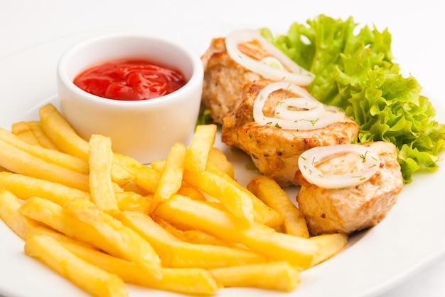 Hermoso menú fotográfico de primer plano de sabrosas papas fritas frescas y carne y ensalada en un plato sobre un fondo blanco