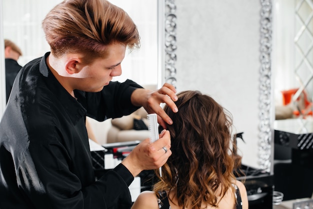 En un hermoso y moderno salón de belleza, una estilista profesional hace un corte de pelo y un peinado para una niña. Belleza y moda.