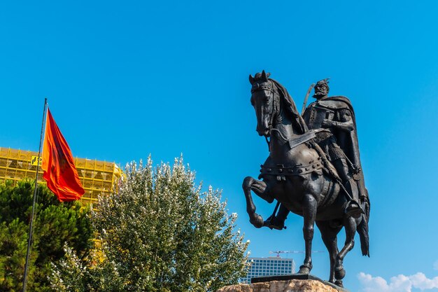 El hermoso monumento al caballo Skanderbeg en la plaza Skanderbeg en Tirana y la bandera roja de Albania