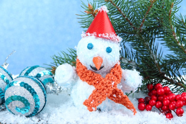 Hermoso muñeco de nieve y decoración navideña, sobre fondo azul.