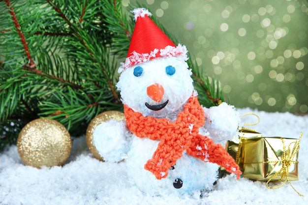 Hermoso muñeco de nieve y decoración navideña, sobre fondo brillante