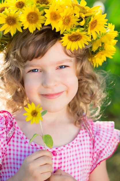 Hermoso niño en corona de girasol de primavera