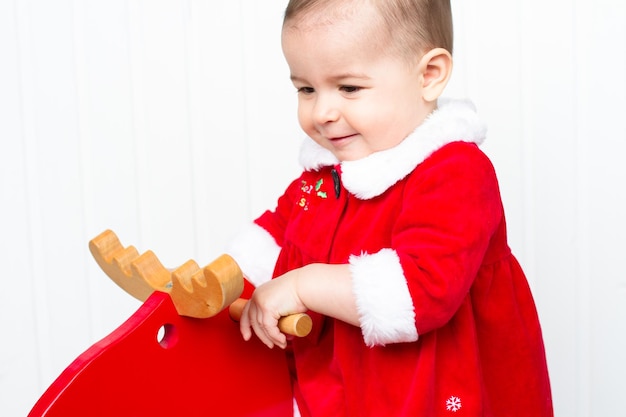 Hermoso niño feliz Navidad con reno rojo de madera