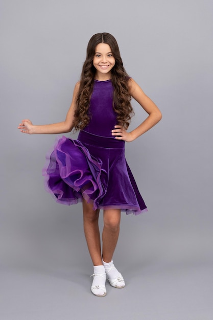 Hermoso niño feliz con pelo largo y rizado en vestido de salón de baile de cuerpo entero, junior.