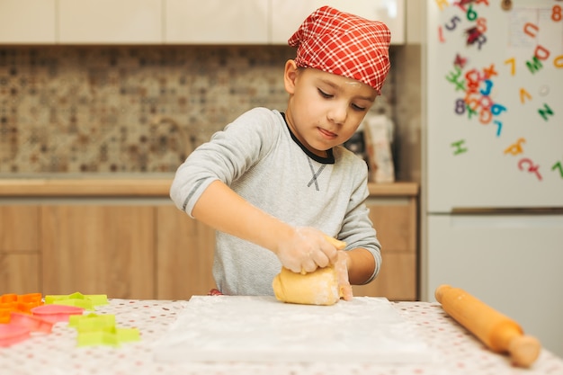 Hermoso niño haciendo masa para galletas