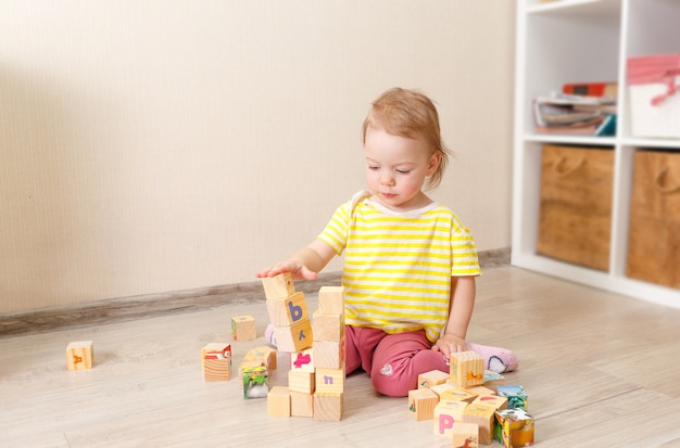 Hermoso niño juega con cubos de madera