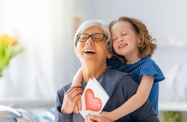 Foto hermoso niño lindo felicitando a la abuela y dándole una postal mujer