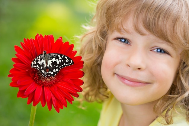 Hermoso niño con mariposa en el parque de primavera Niño feliz jugando al aire libre