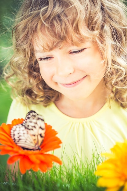 Hermoso niño con mariposa en el parque de primavera Niño feliz jugando al aire libre