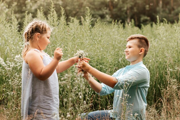 Hermoso niño y niña en un parque niño dando flores a la niña Concepto de amistad