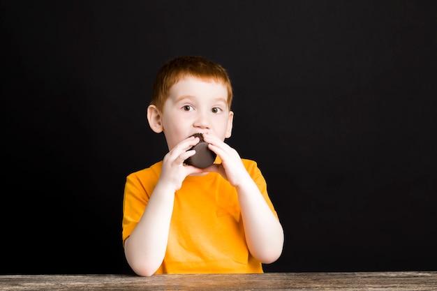 Un hermoso niño pelirrojo con una magdalena de chocolate.