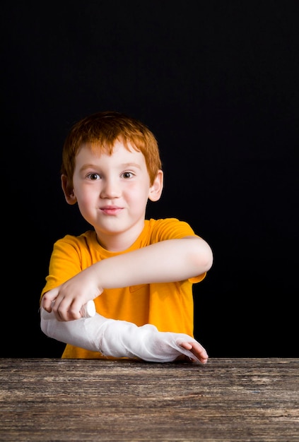 Un hermoso niño pelirrojo con una mano dañada.