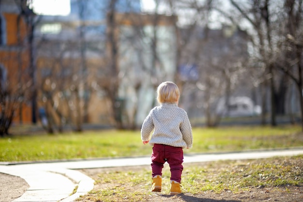 Hermoso niño pequeño caminando al aire libre en el cálido día de primavera