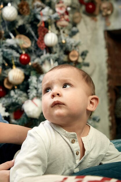 Hermoso niño soñando con cabañas bajo el árbol de Navidad Concepto de Navidad y niños esperando un milagro