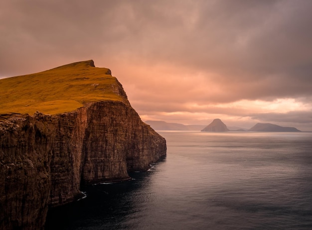 Hermoso paisaje de acantilados rocosos junto al mar en las Islas Feroe bajo un cielo nublado