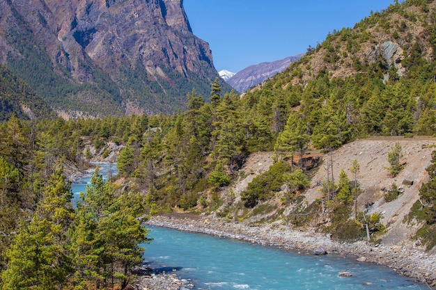 Hermoso paisaje con altas montañas del Himalaya que curvan el bosque verde del río y el cielo azul en otoño en Nepal