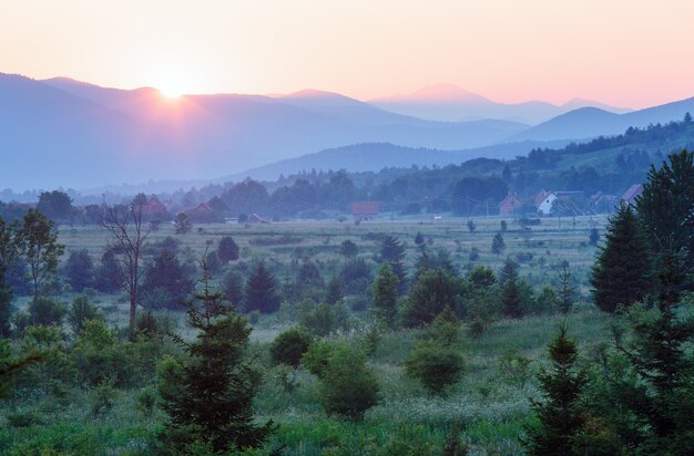 Hermoso paisaje campestre de verano con puesta de sol sobre las montañas