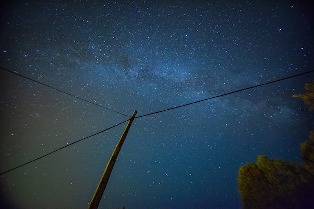 Hermoso paisaje de cielo nocturno con estrellas y poste eléctrico.