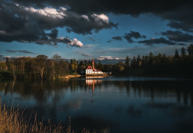 Hermoso paisaje dramático con un castillo junto al lago y oscuras nubes de tormenta.