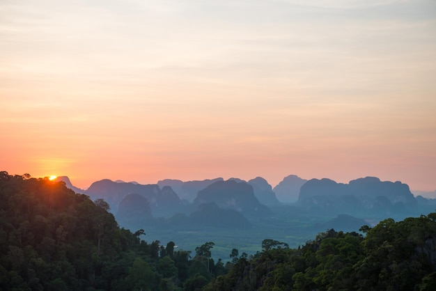 Hermoso paisaje con una espectacular puesta de sol, selva tropical y una empinada cordillera en el horizonte. Krabi, Tailandia