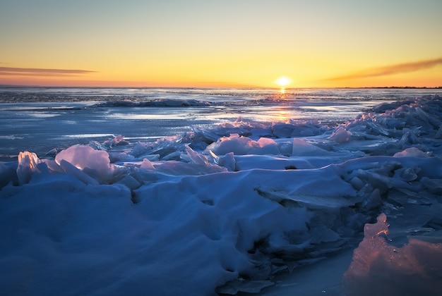 Hermoso paisaje invernal con cielo ardiente al atardecer y lago congelado