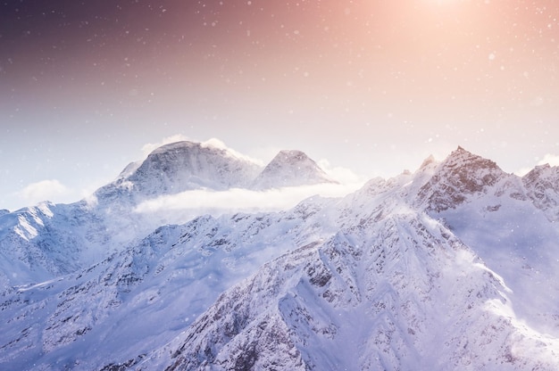 Hermoso paisaje invernal con montañas cubiertas de nieve al atardecer.