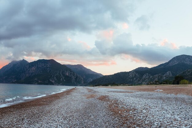 Hermoso paisaje de mar y montañas en la puesta de sol. Playa por la noche en Turquía. Día nublado.