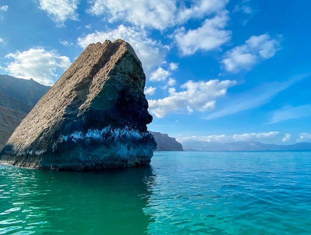 Hermoso paisaje marino con una roca en agua turquesa y cielo azul.