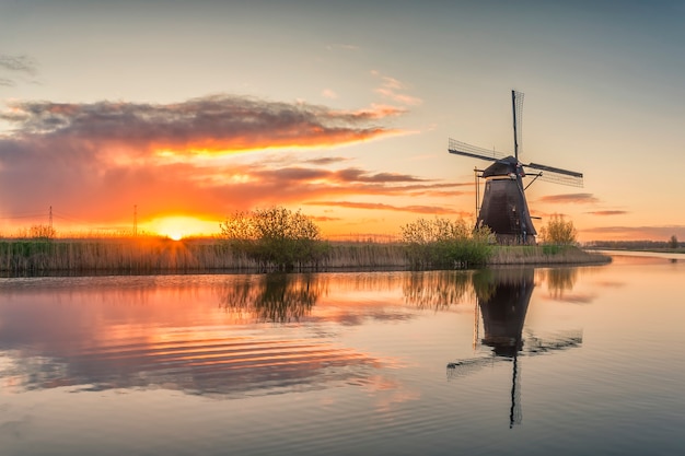 Hermoso paisaje con molinos de viento y majestuoso cielo reflejo en el agua