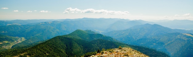 Hermoso paisaje de montaña, con picos cubiertos de bosques y un cielo nublado.