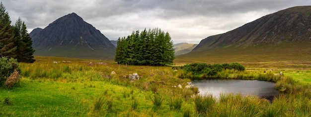 Hermoso paisaje panorámico de altas montañas, árboles y lagos en el valle de Glencoe Escocia