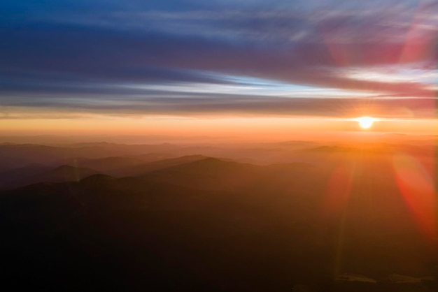 Hermoso paisaje panorámico de montaña con picos brumosos y valle brumoso al atardecer