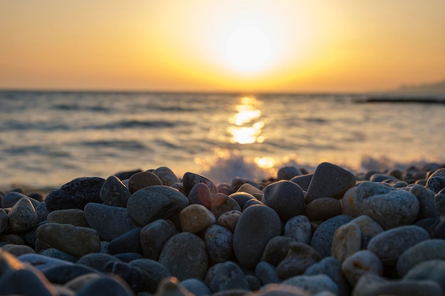 Hermoso paisaje de puesta de sol en el mar Reflejo del espejo del amanecer en guijarros húmedos Luz solar dorada sobre las olas del mar Cerca de la espuma de la marea y la costa de guijarros del mar