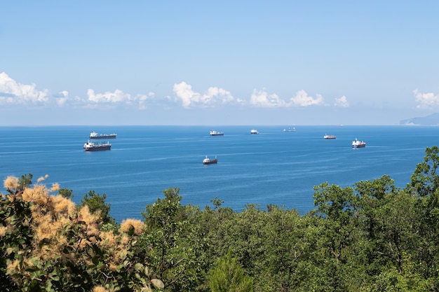 Hermoso paisaje de verano, nubes de mar azul sobre el horizonte y varios buques de carga en primer plano