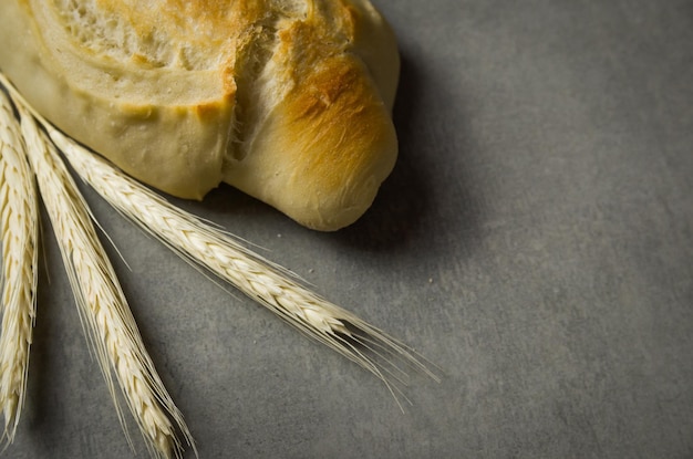 Hermoso pan de masa fermentada sobre fondo gris con flor de trigo seco