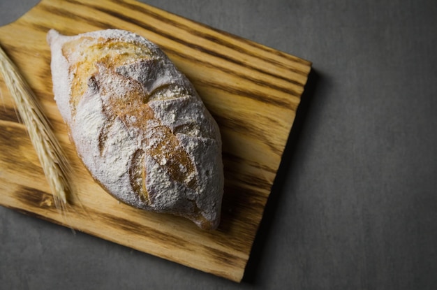 Hermoso pan de masa fermentada sobre fondo gris con flor de trigo seco