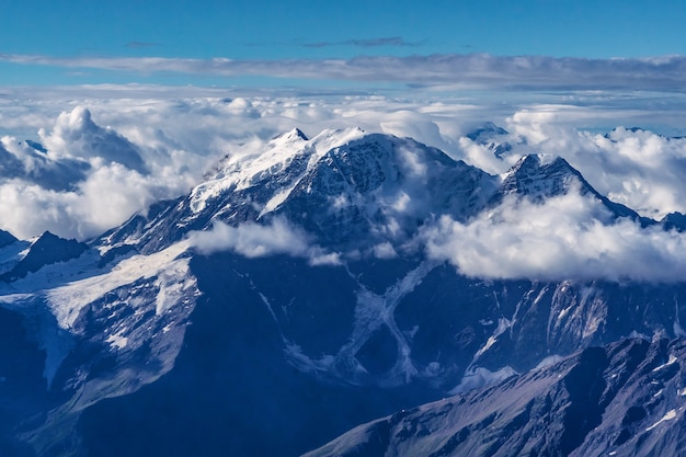 Hermoso panorama de altas montañas rocosas con poderosos glaciares y picos nevados contra el cielo azul y las nubes