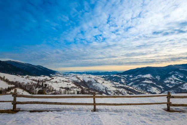 Hermoso panorama de las cadenas montañosas cubiertas de nieve y divididas en rutas de senderismo con vistas al cielo nublado y al atardecer